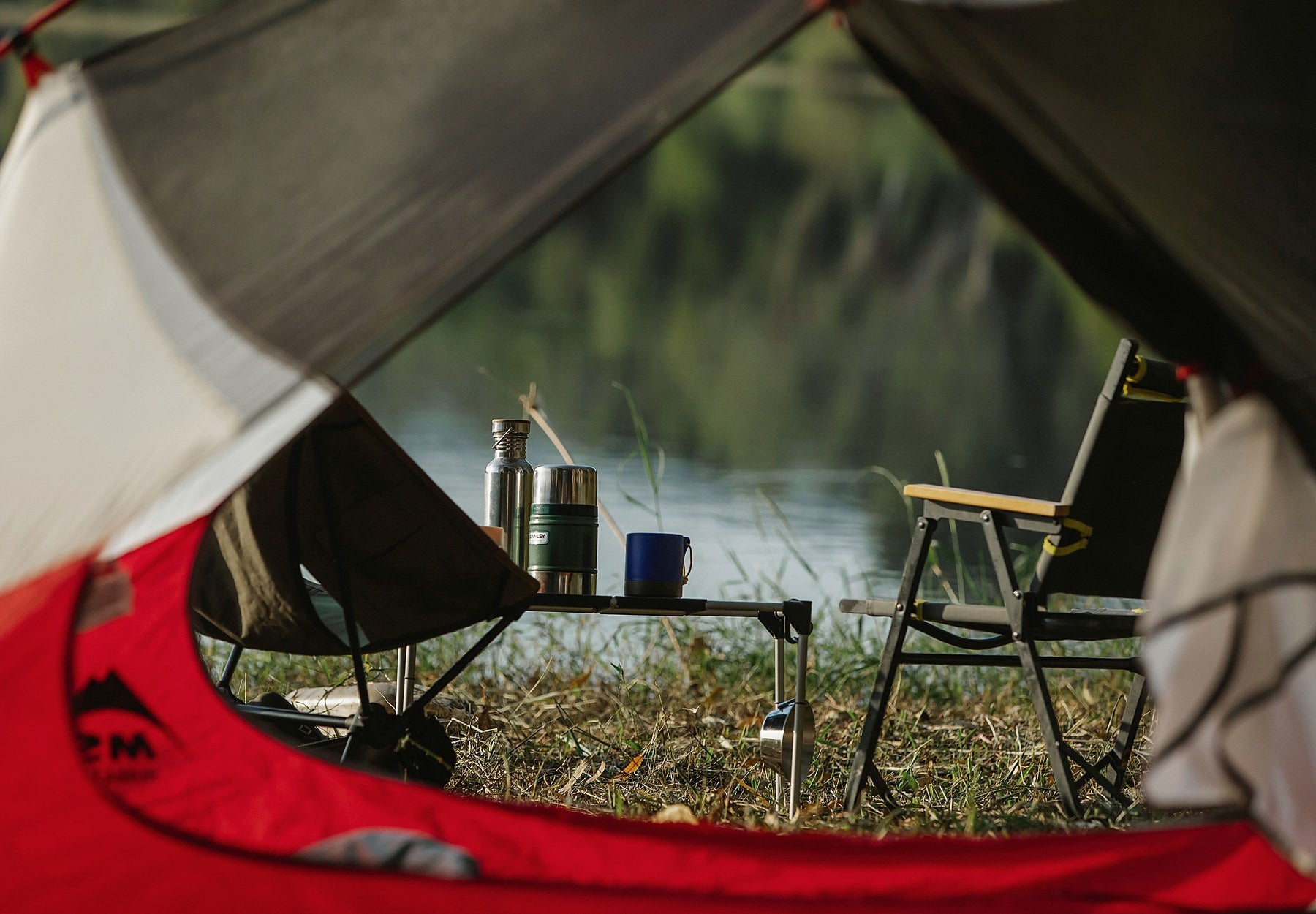 Camping chairs and a compact table beside a lake