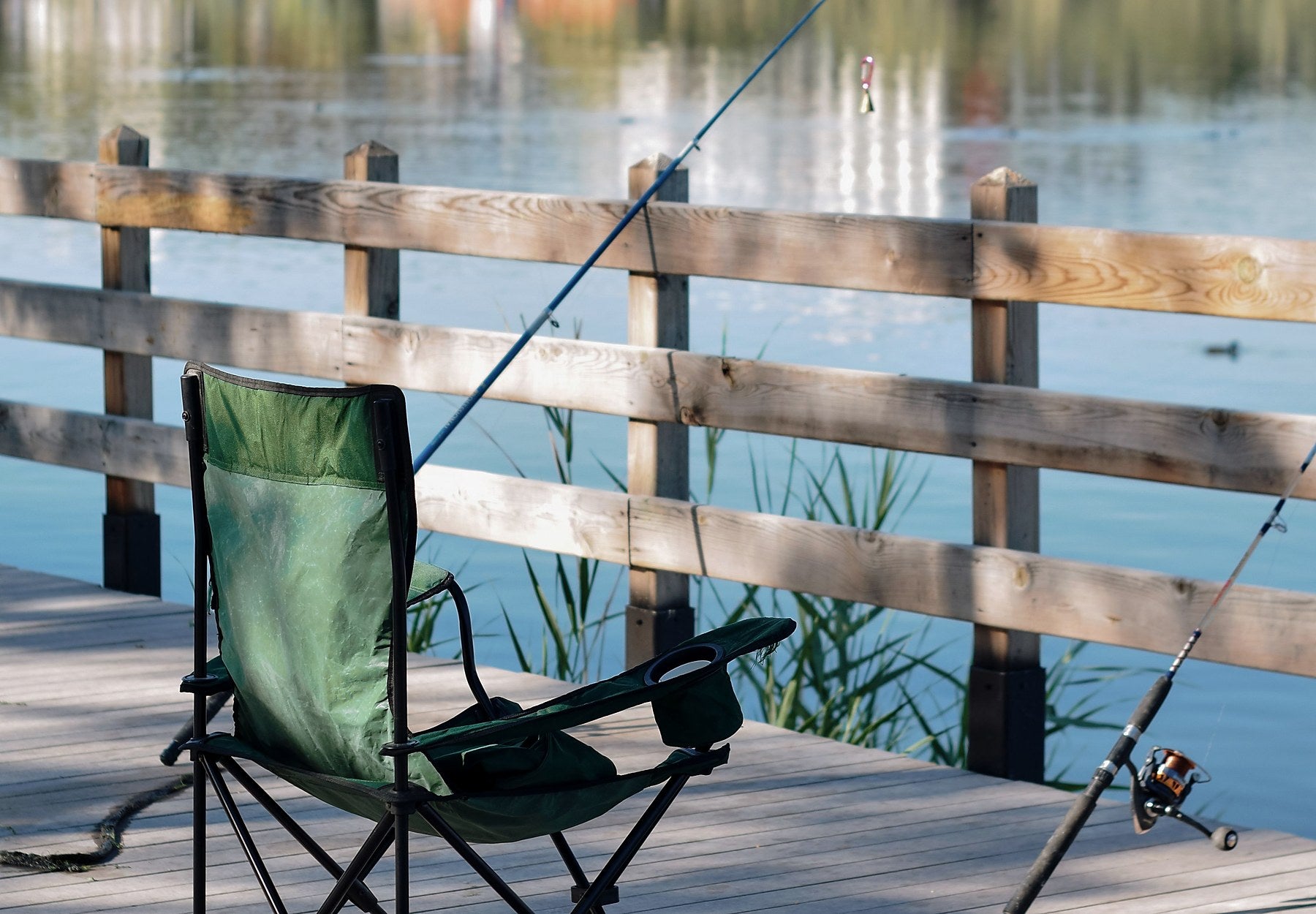 Folding chair and fishing rods beside water