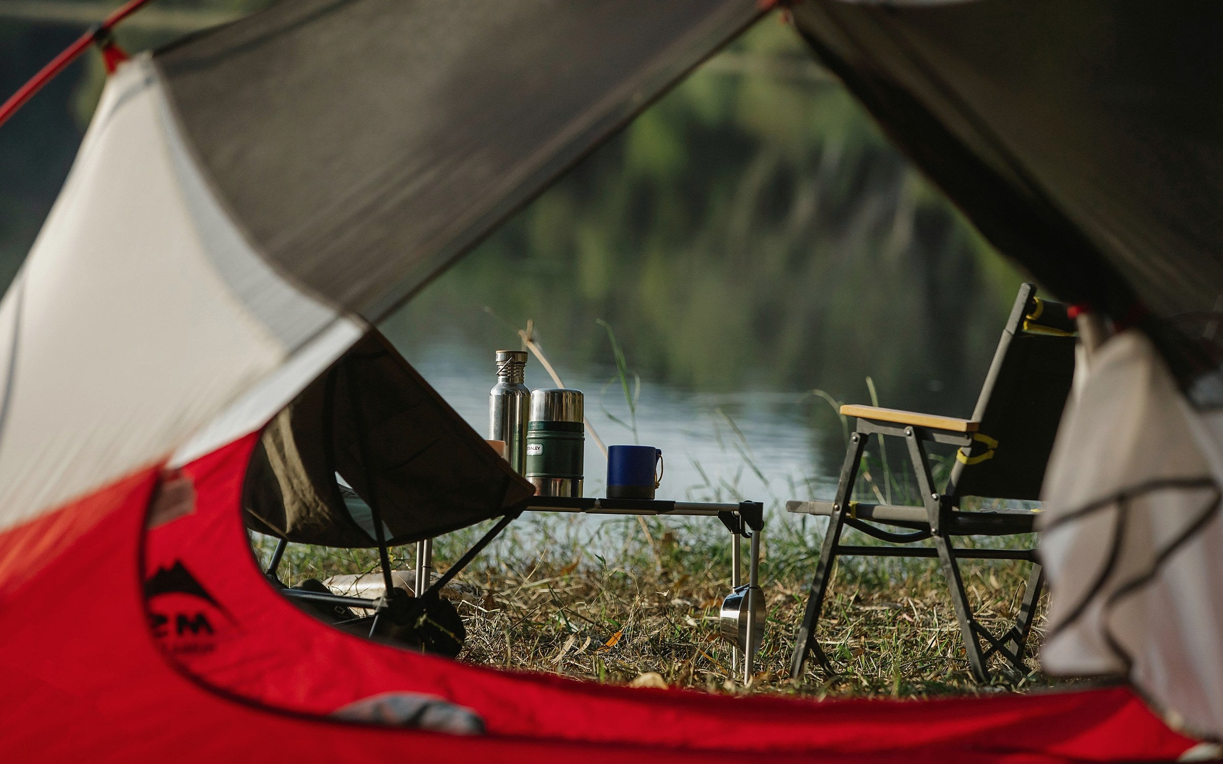 Portable camping chairs and a compact table beside a lake